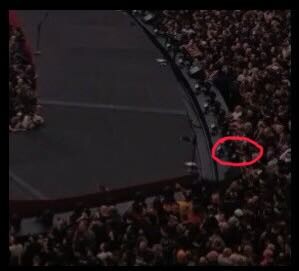 An overhead view of the stage edge and the packed floor crowd inside the Sphere, with a red circle around Wesley on the rail near the tip of the stage